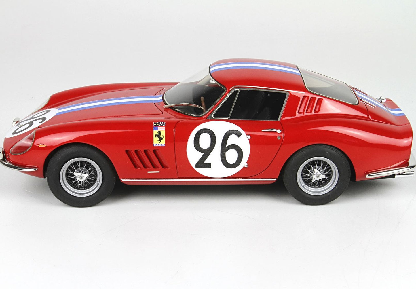 Voiture de course Ferrari vintage rouge avec le numéro 26 et des bandes bleues et blanches, disponible sur Vroomi.