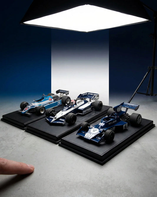 Three classic Formula 1 model cars displayed on black bases under studio lighting, available on Vroomi