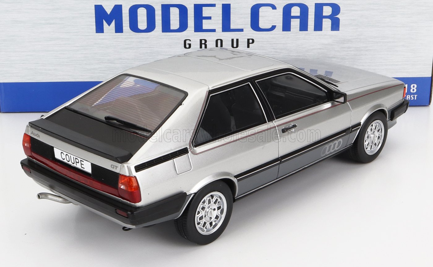 Silver Audi GT coupe 1/18 scale model car with detailed black and red accents, displayed on white surface, available at Vroomi