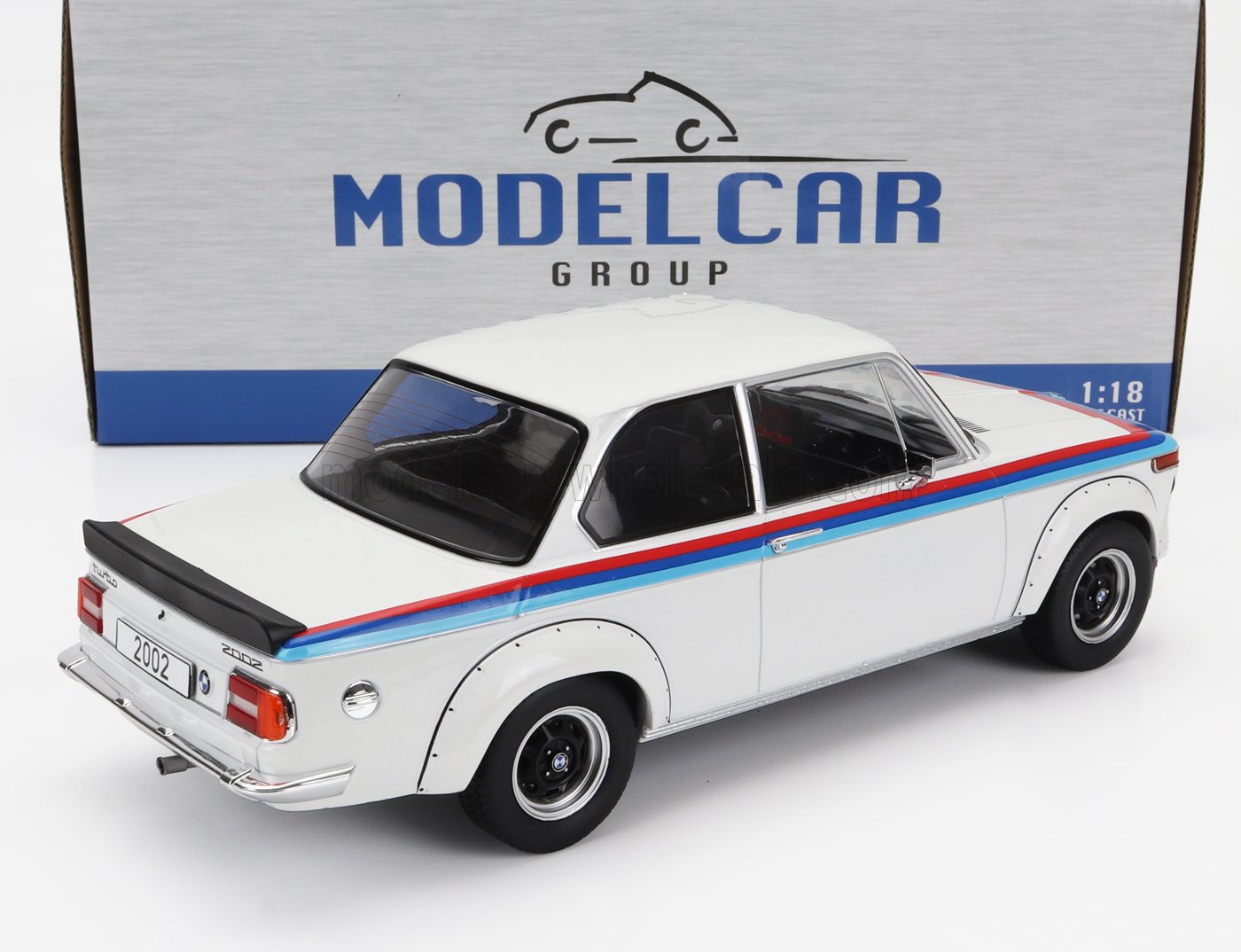 White BMW 2002 Turbo scale model car with blue and red stripes, displayed in front of Model Car Group box, available at Vroomi