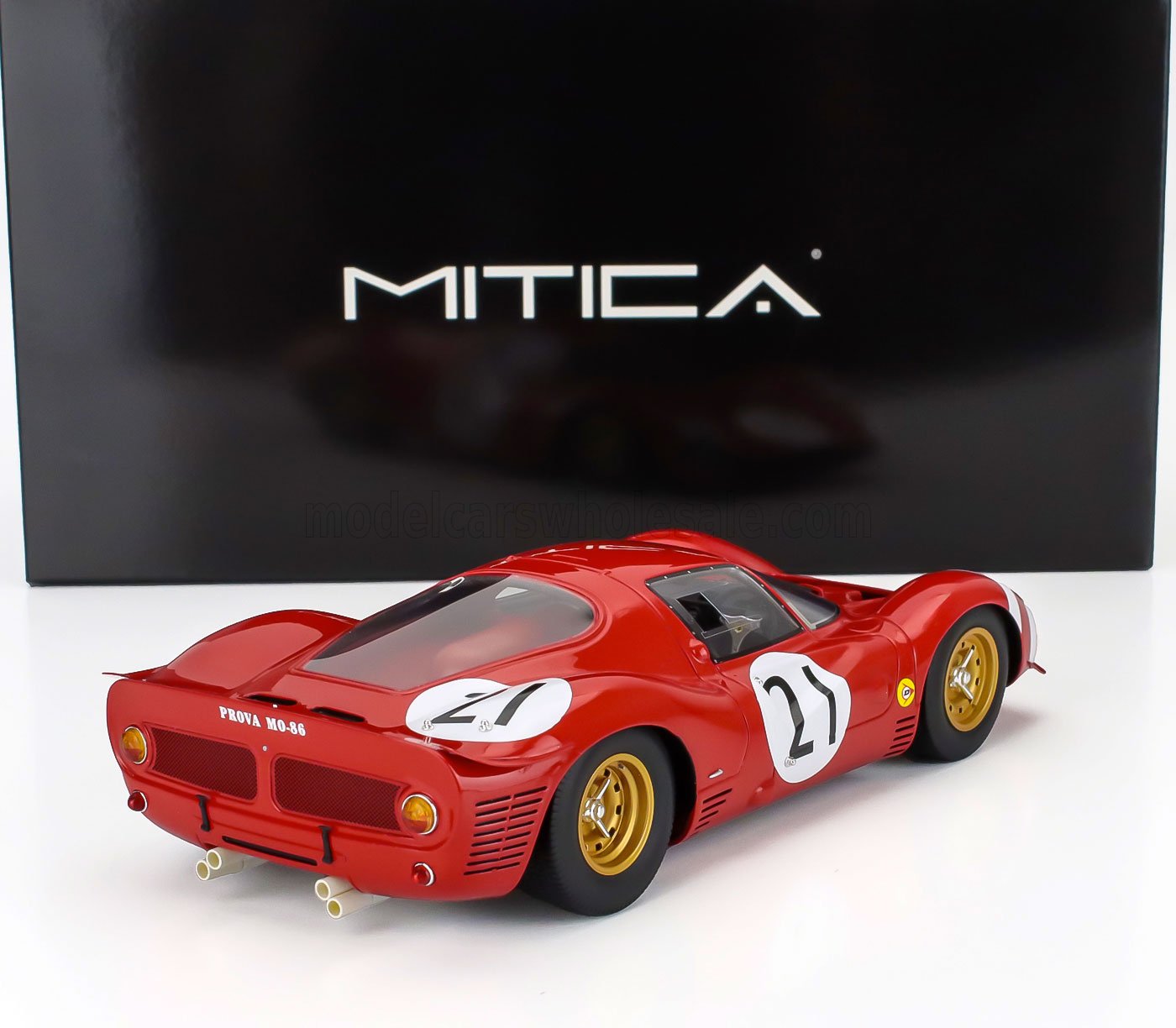 Maquette de voiture de course vintage rouge portant le numéro 21 et dotée de jantes dorées, présentée devant un coffret Mitica noir, proposée sur Vroomi