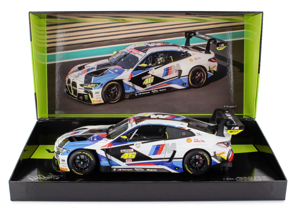 Coche a escala BMW M4 GT3 con decoración Gulf, expuesto en caja de coleccionista Vroomi con fondo de carrera