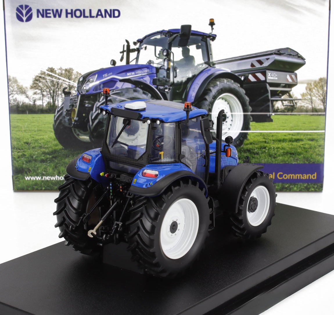 Modellino in scala di trattore blu New Holland in metallo pressofuso, esposto su base nera con confezione che mostra il trattore vero in un campo, disponibile presso Vroomi.