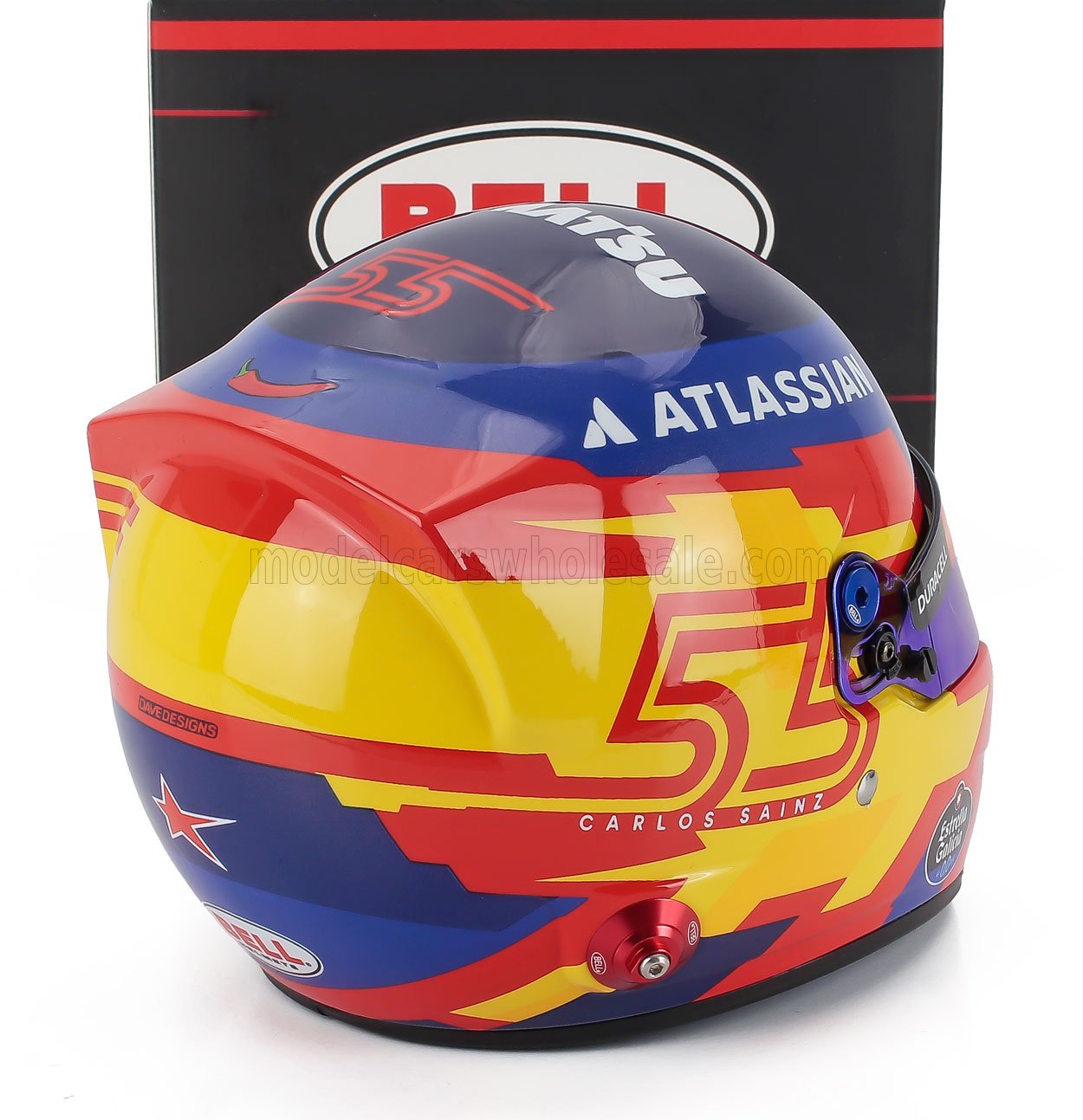 Carlos Sainz racing helmet scale model car replica by Vroomi, featuring vibrant red, yellow, blue design with sponsor logos.