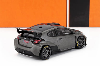 Gray Toyota GR Yaris rally car model with black roof and spoiler on white surface, featured on Vroomi