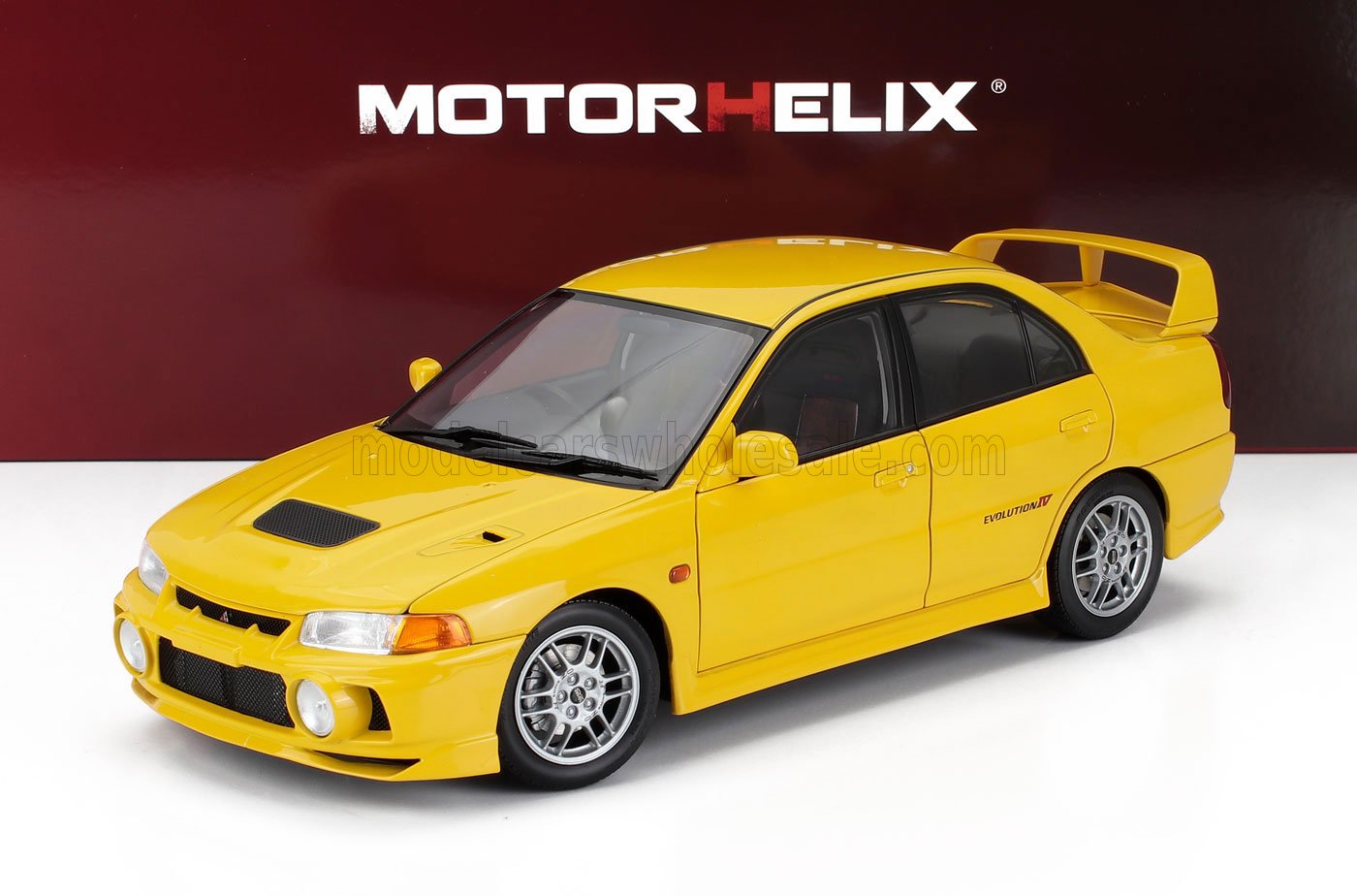 Yellow Mitsubishi Evolution IV model car with spoiler, displayed under MotorHelix logo, also accessible on Vroomi