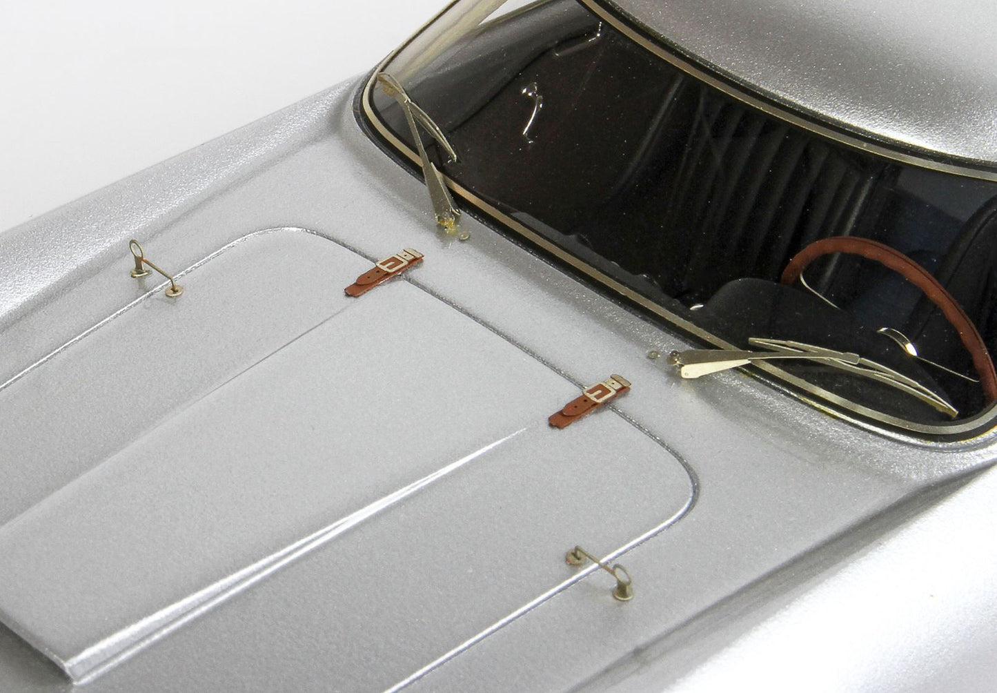 Silver classic car hood with leather straps and vintage windshield, available through Vroomi platform