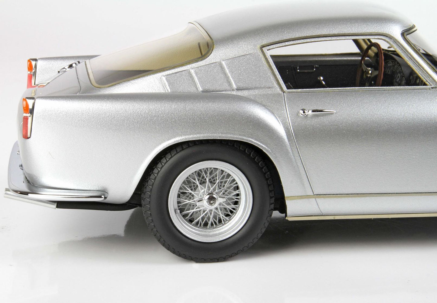 Silver classic sports car detailed side view with wire spoke wheel, featured on Vroomi