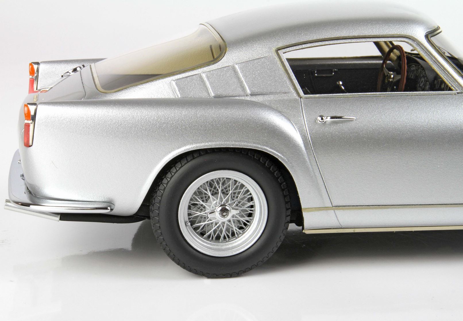 Silver classic sports car detailed side view with wire spoke wheel, featured on Vroomi