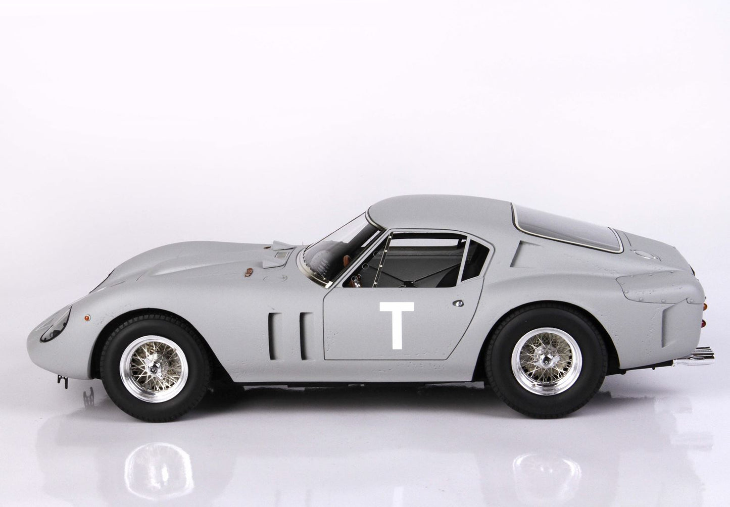 Side view of vintage gray race car with white letter T on door, classic wire wheels, featured on Vroomi