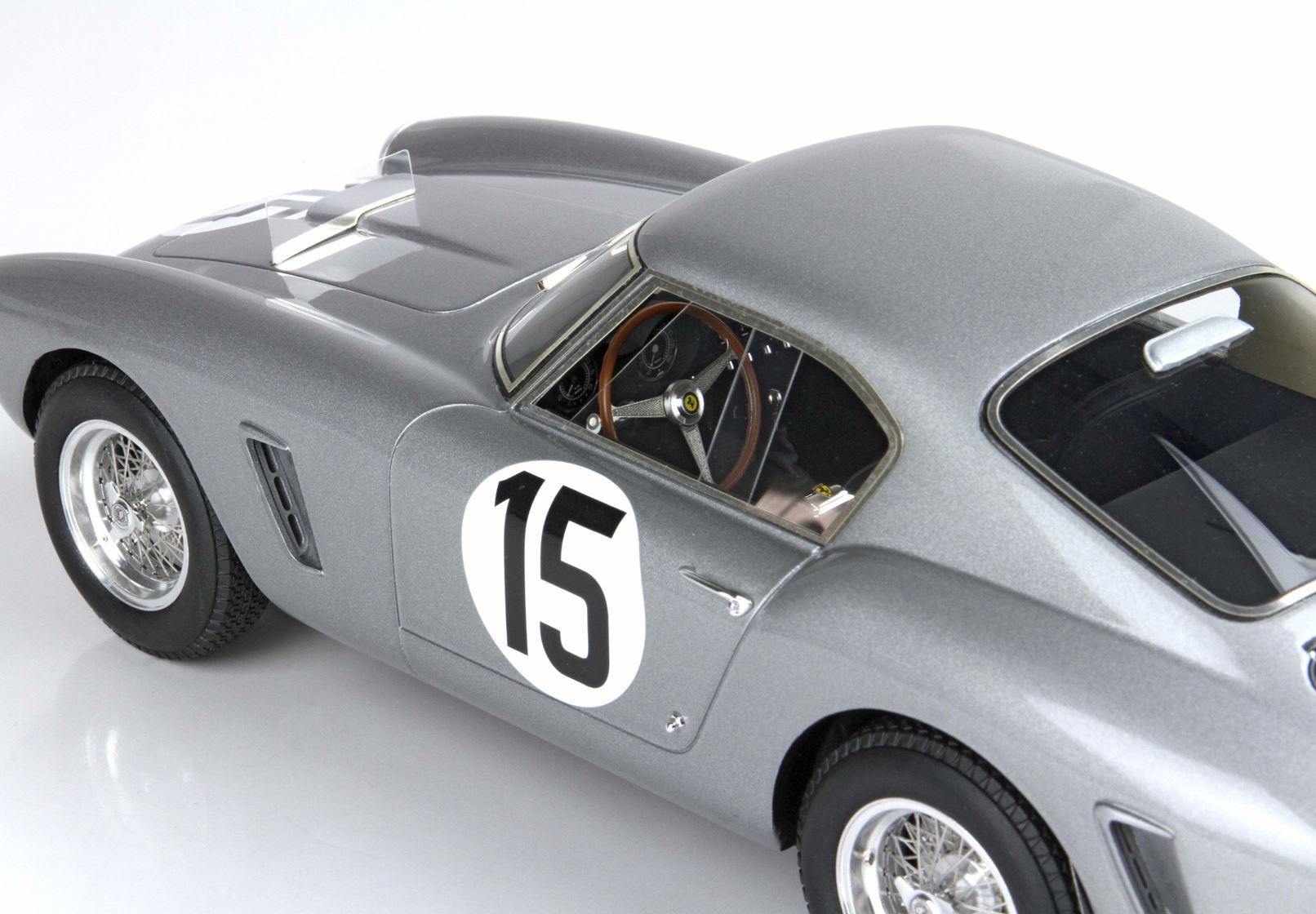 Silver vintage race car with number 15, classic wire wheels, and wooden steering, available via Vroomi