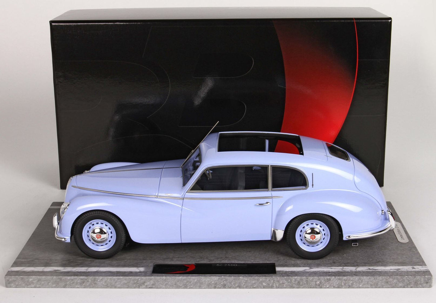 Light blue classic model car displayed on marble base with black and red backdrop, available on Vroomi