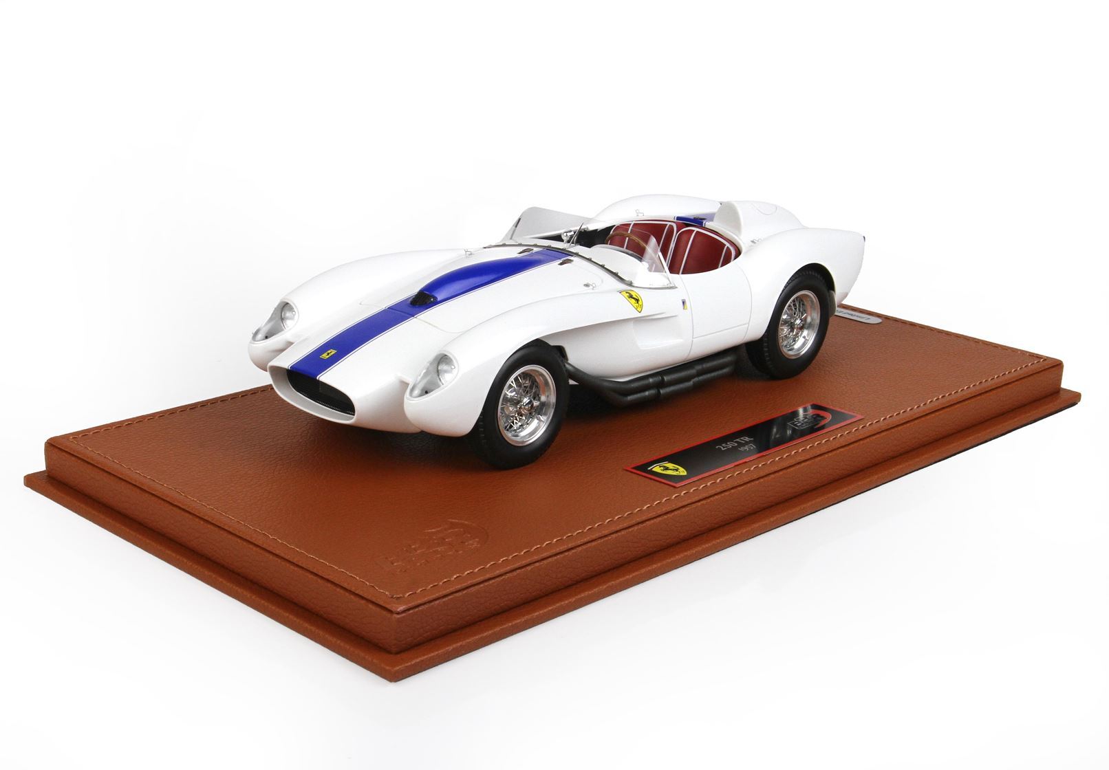 White 1957 Ferrari 250 TR model car with blue stripe on brown leather display base, available on Vroomi