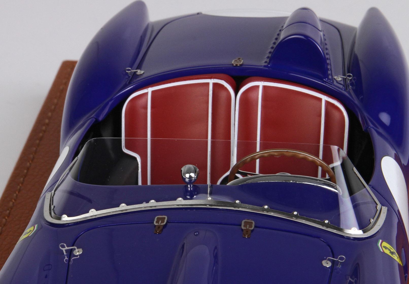 Close-up top view of blue classic race car with red leather seats and wooden steering wheel, available on Vroomi