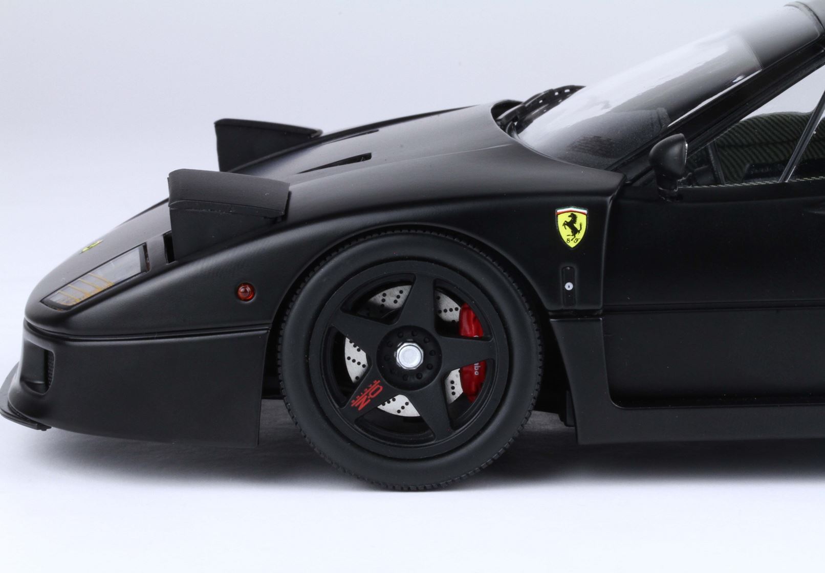 Close-up of black Ferrari car front wheel with red brake caliper and logo, offered on Vroomi