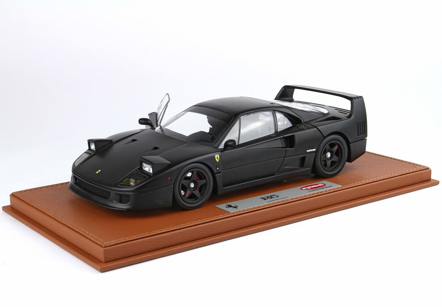Matte black Ferrari F40 scale model with open door on brown leather display base, available on Vroomi
