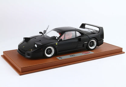 Black Ferrari F40 model car with raised left door displayed on brown leather base, available through Vroomi