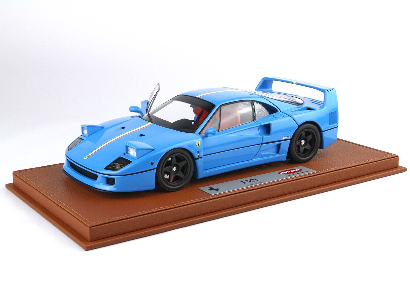 Blue Ferrari F40 model car with red interior and open door on leather display base, now sellable via Vroomi