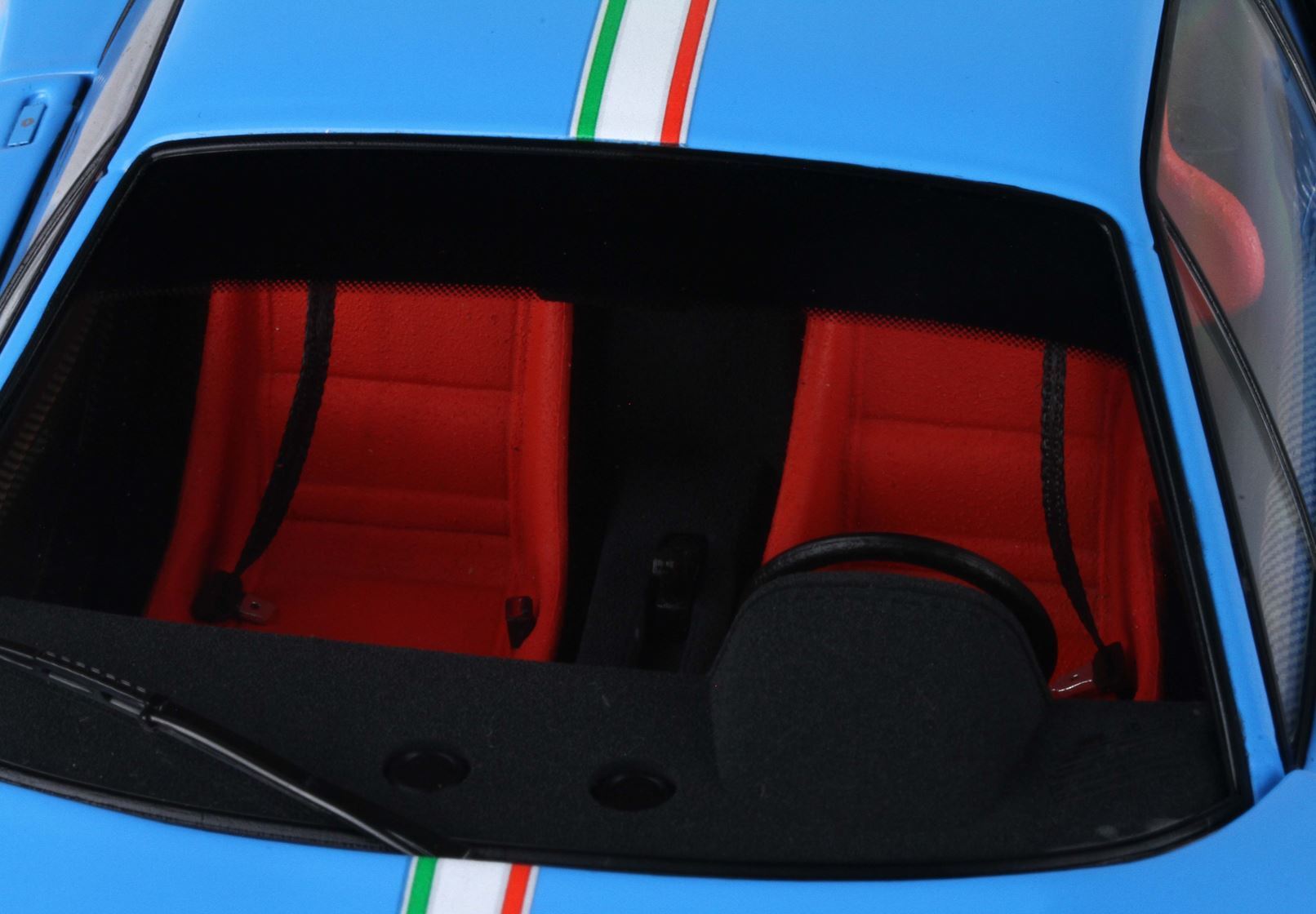 Blue sports car interior with red seats, black steering wheel, and Italian flag stripe, available on Vroomi