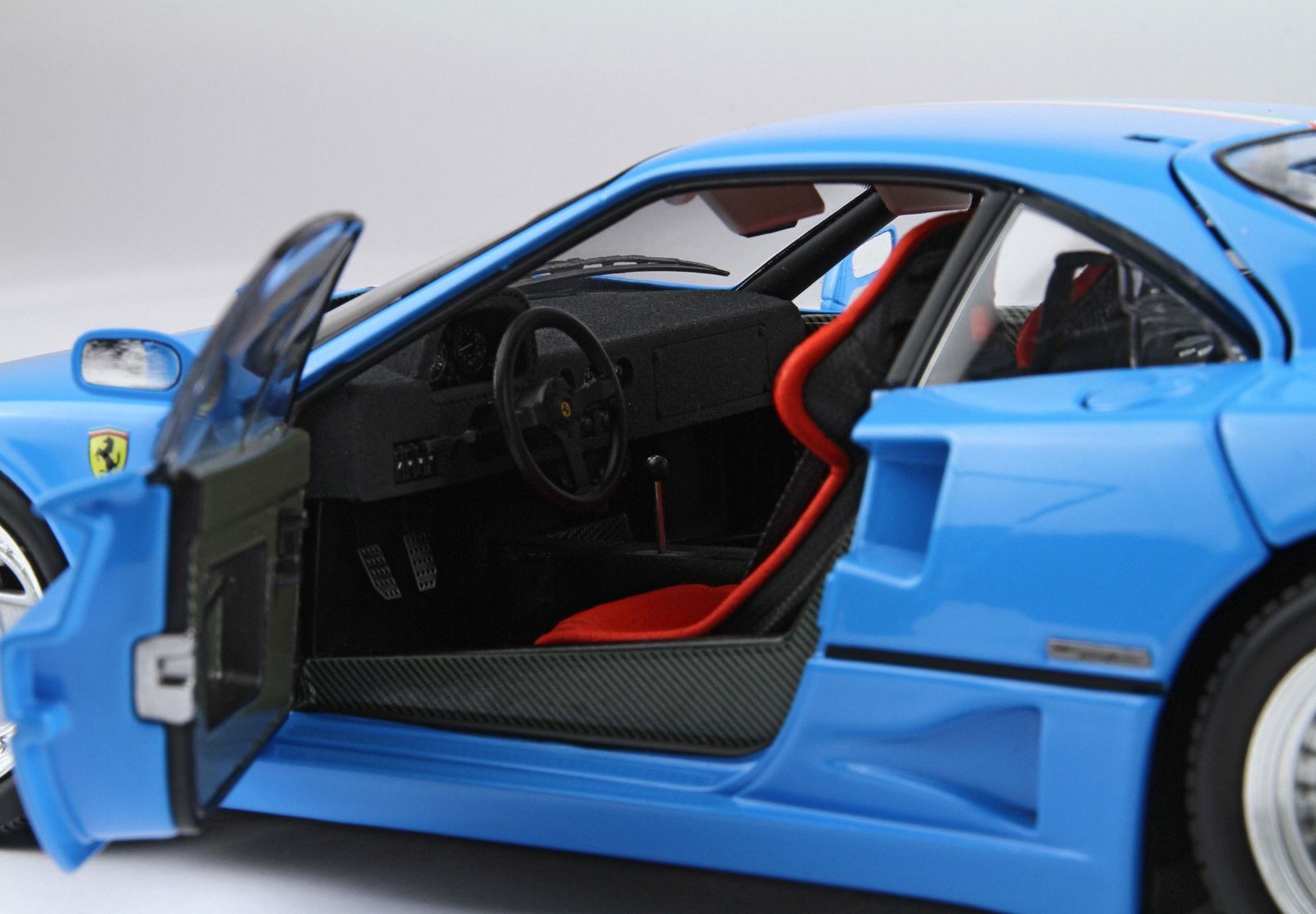 Blue Ferrari model car with open door showing red racing seat and detailed interior, available on Vroomi