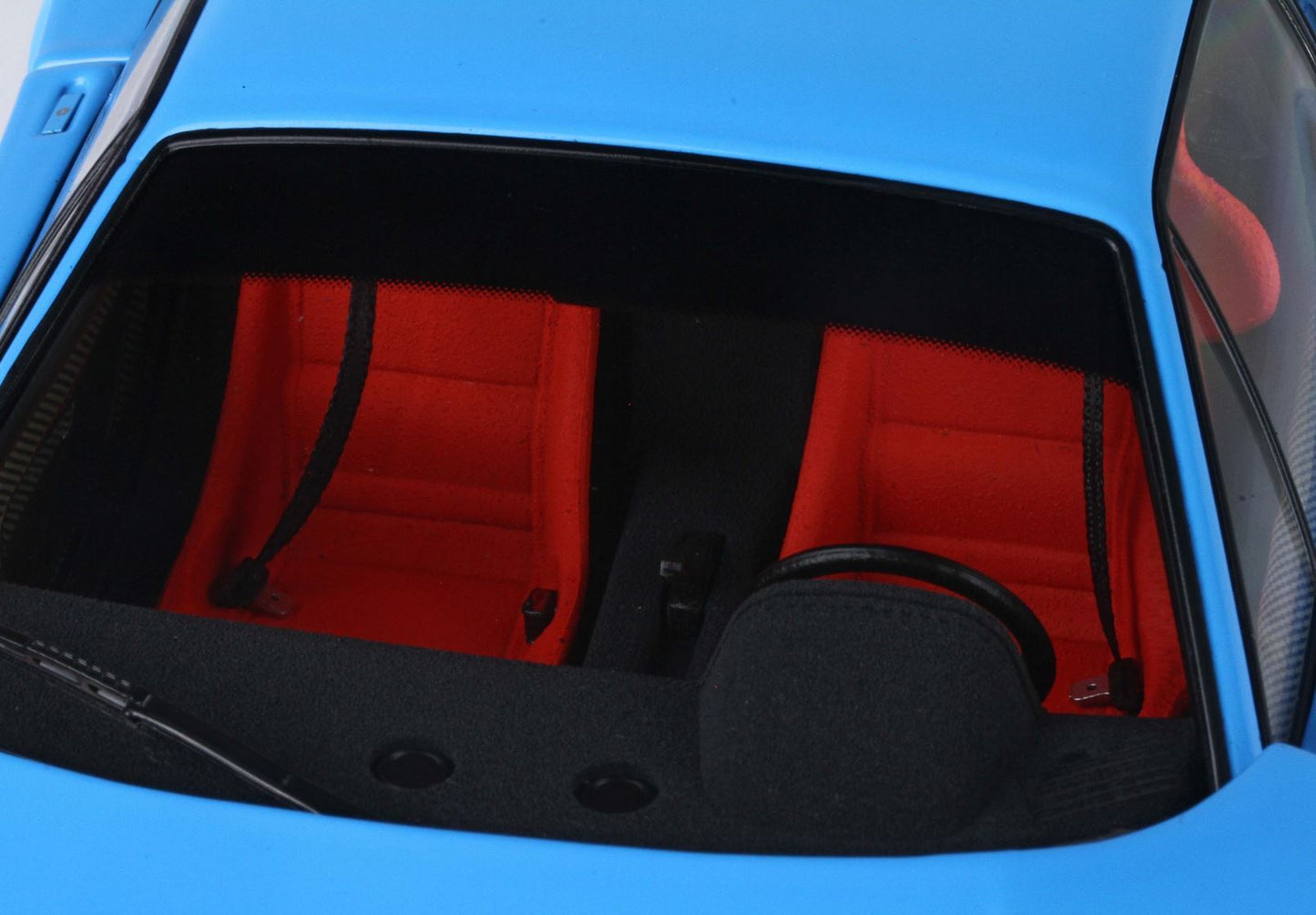 Blue sports car interior with vibrant red racing seats and black steering wheel, available on Vroomi
