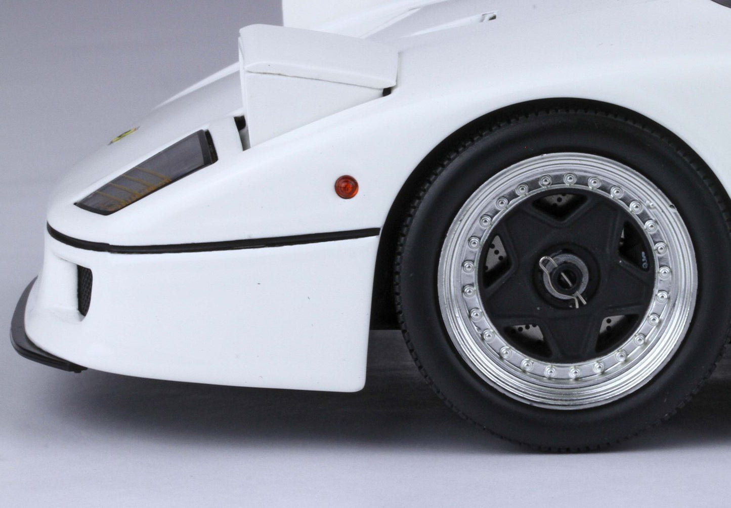 Close-up of white sports car front wheel and side, featuring black and silver rims, available on Vroomi