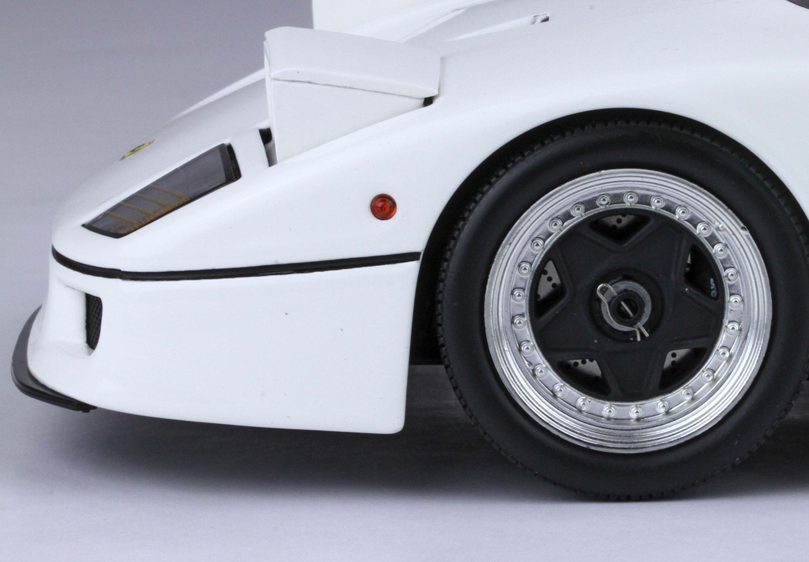 Close-up of white sports car front wheel and side, featuring black and silver rims, available on Vroomi