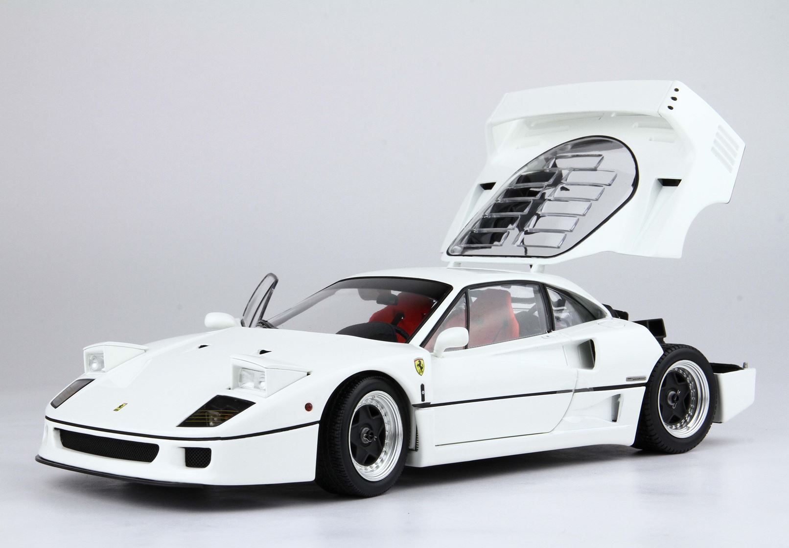 White Ferrari F40 sports car model with open rear engine cover and driver's door, showcasing red seats, available via Vroomi