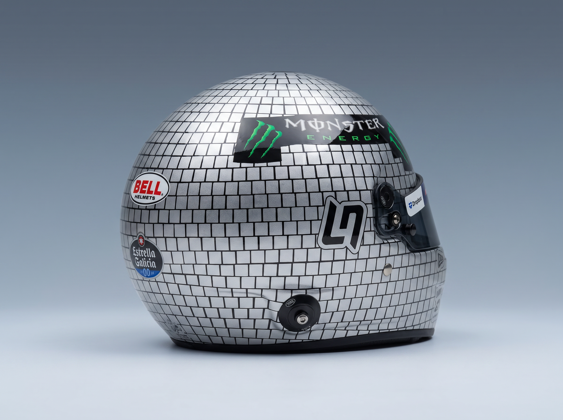 Silver disco-ball style racing helmet with Monster Energy, Bell, and Estrella Galicia logos — scale model car accessory at Vroomi