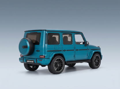 Tealfarbenes Mercedes-AMG G63-Modellauto von Vroomi, detailgetreue Druckguss-Nachbildung mit schwarzen Rädern und Reserverad am Heck.