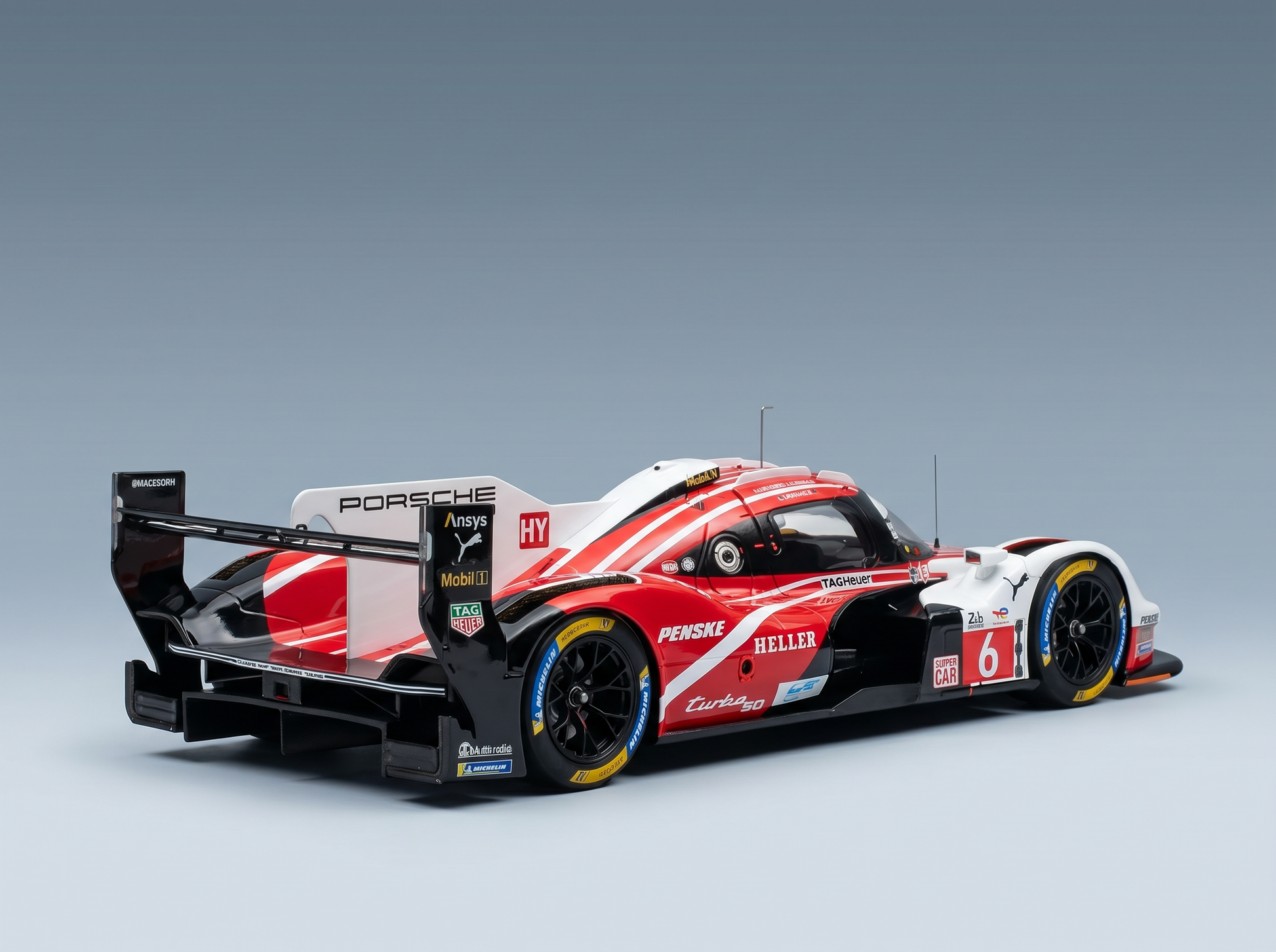 Maquette de Porsche 963 LMDh rouge et blanche, arborant les logos de Penske, TAG Heuer et Michelin, présentée par Vroomi