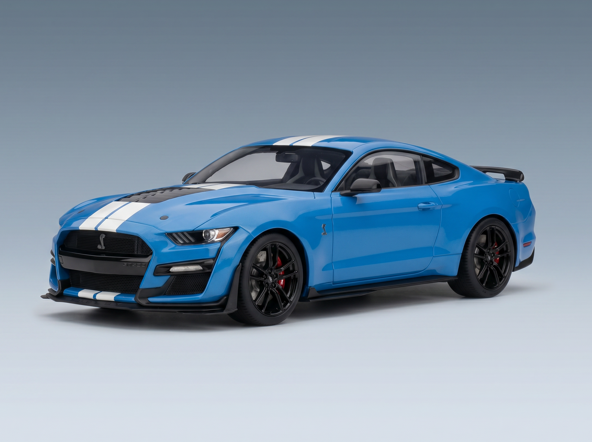 Blaues Ford Mustang Shelby GT500-Modellauto mit weißen Rennstreifen, schwarzen Rädern und Vroomi-Logo