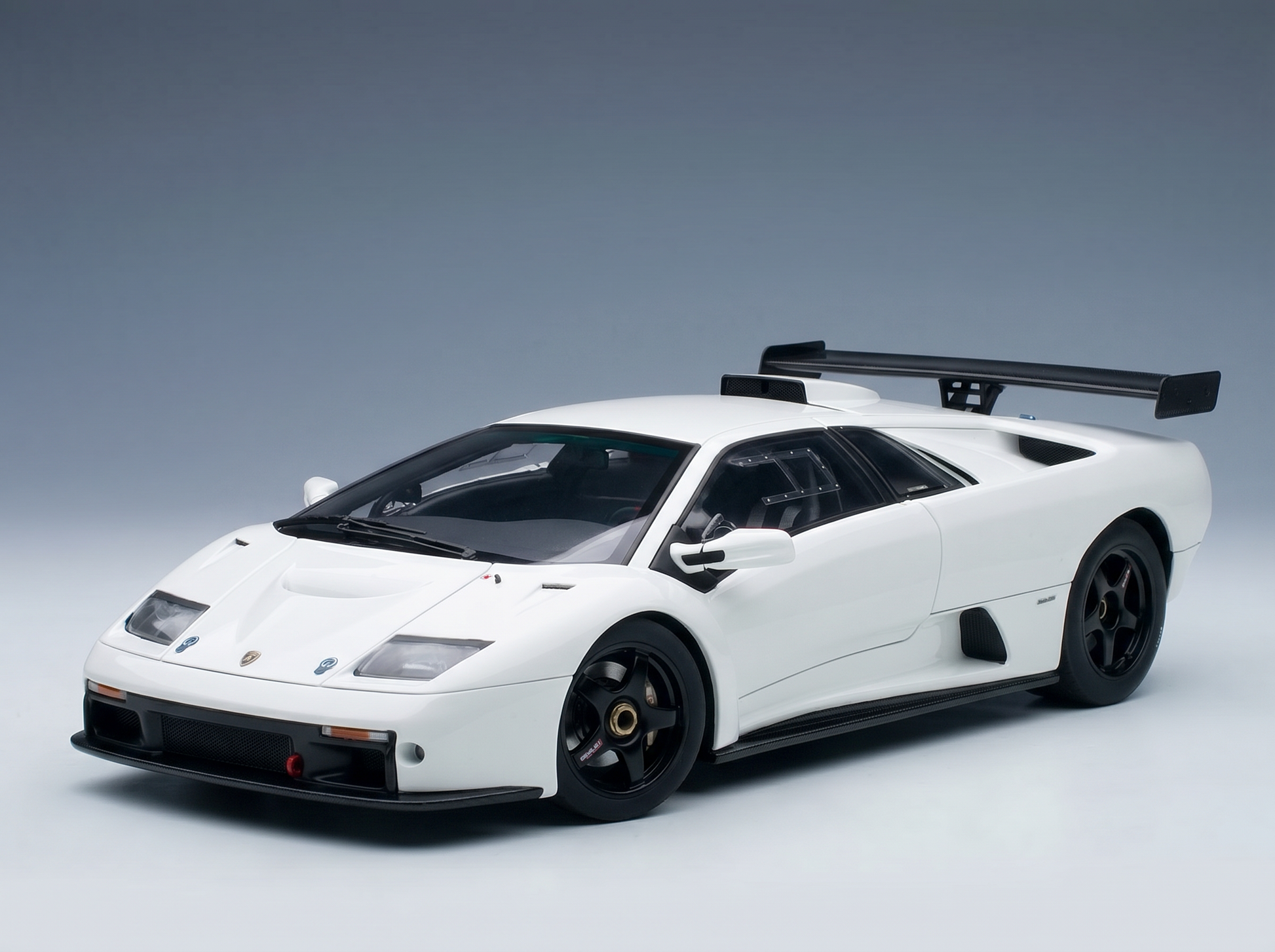 White Lamborghini scale model car with black rims and rear wing, showcased by Vroomi