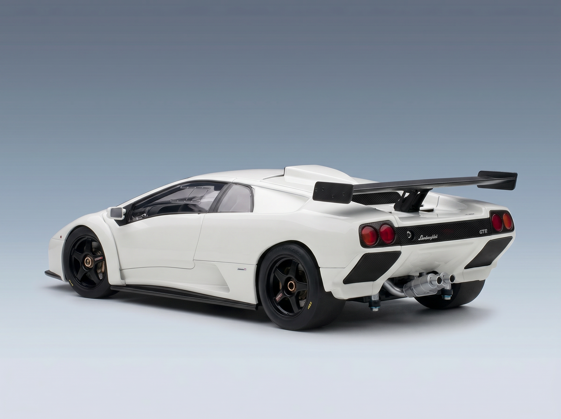 White Lamborghini GTR scale model car with black wheels and rear wing, showcased by Vroomi