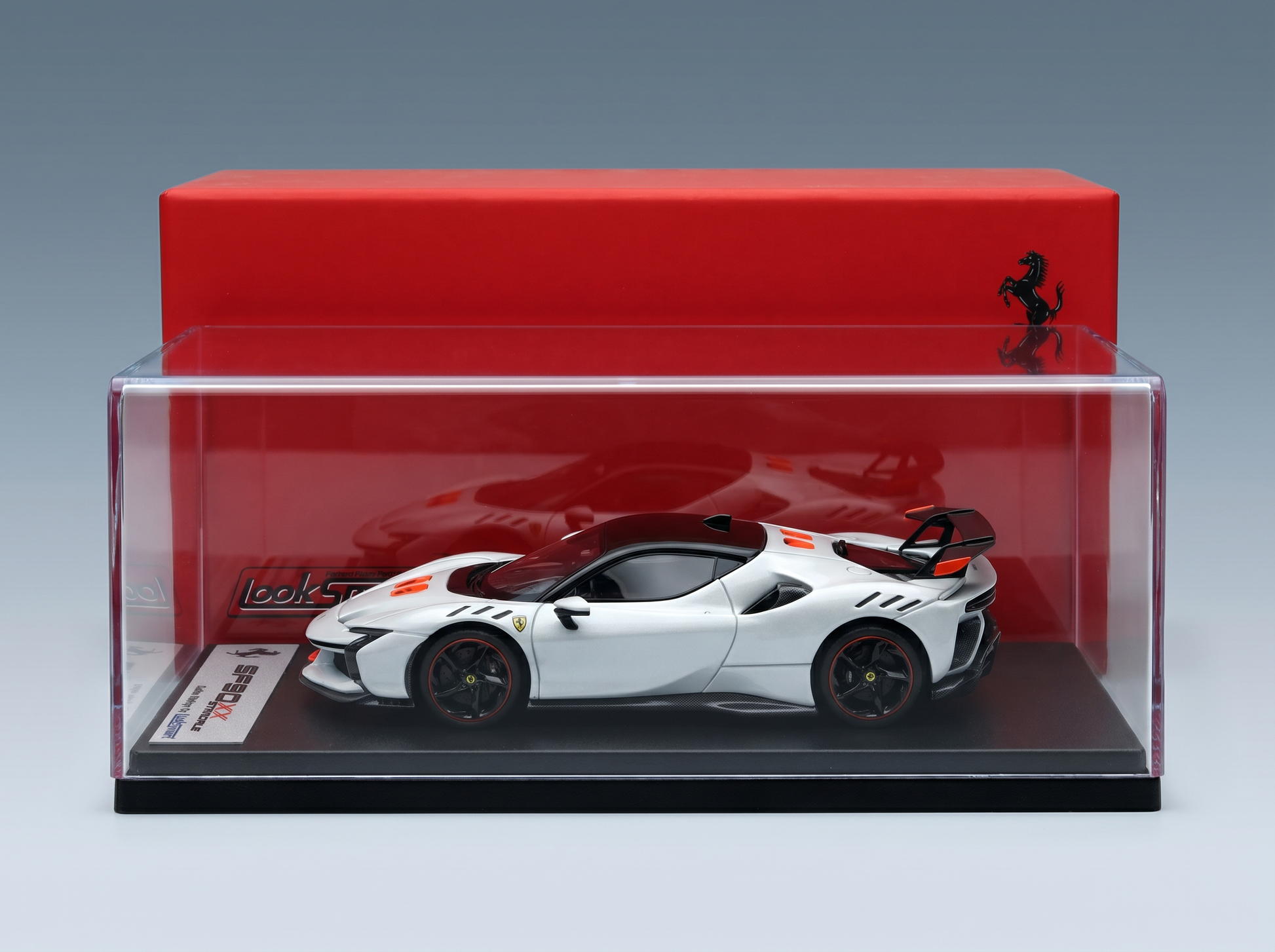 Weißes Ferrari SF90 XX-Modellauto in einer durchsichtigen Vitrine, präsentiert von Vroomi für Sammler