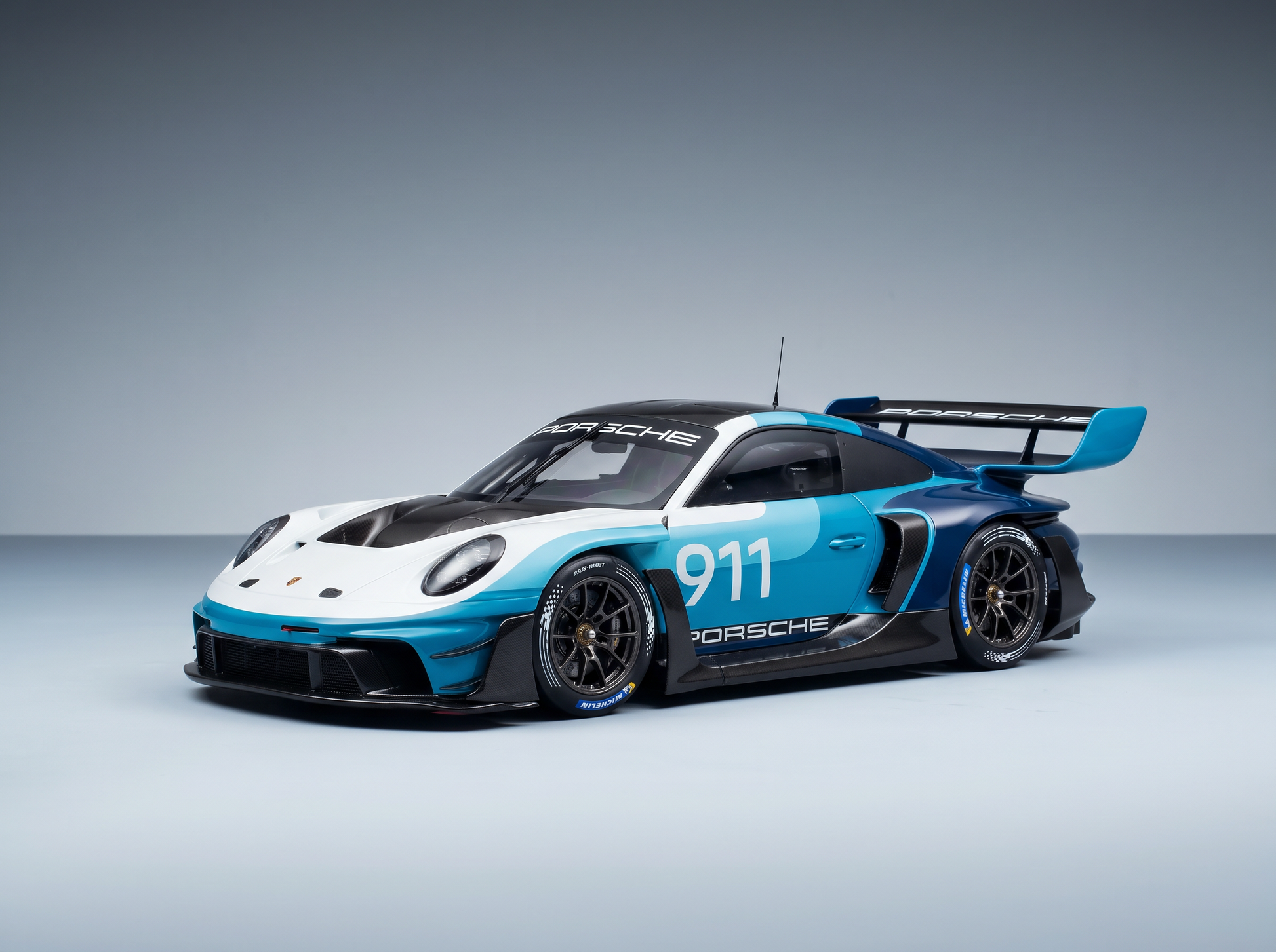Maqueta del Porsche 911 GT3 R con los colores azul y blanco, con adhesivos de competición y diseño aerodinámico, disponible en Vroomi.