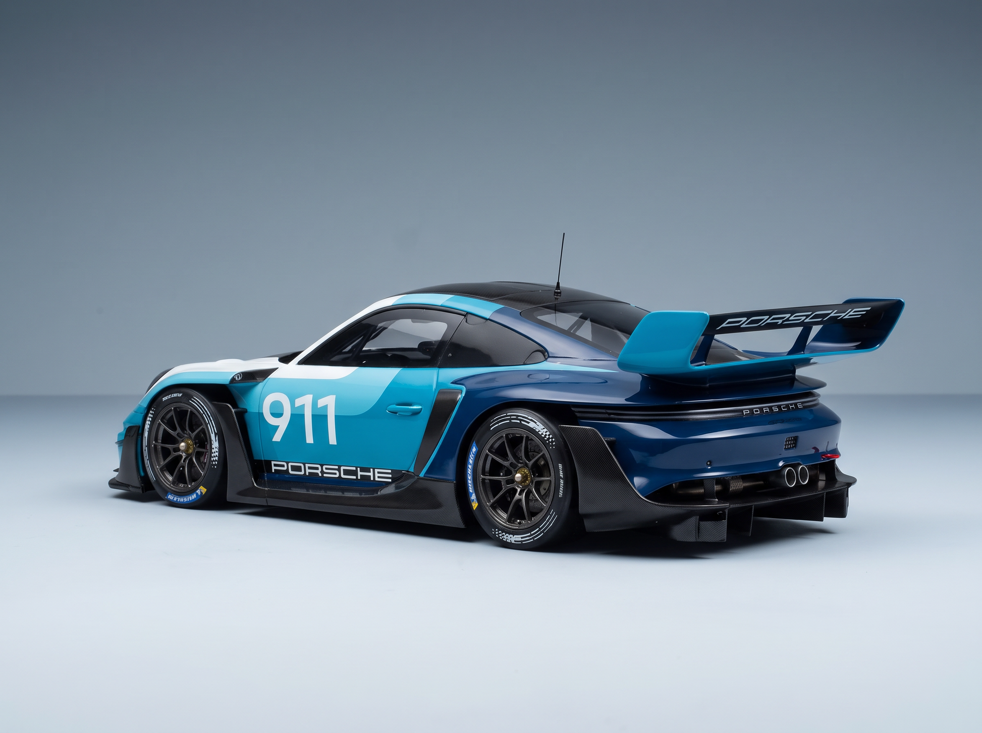 Maqueta a escala del Porsche 911 GT3 R con los colores azul y blanco, con detalles de fibra de carbono y alerón trasero, de Vroomi