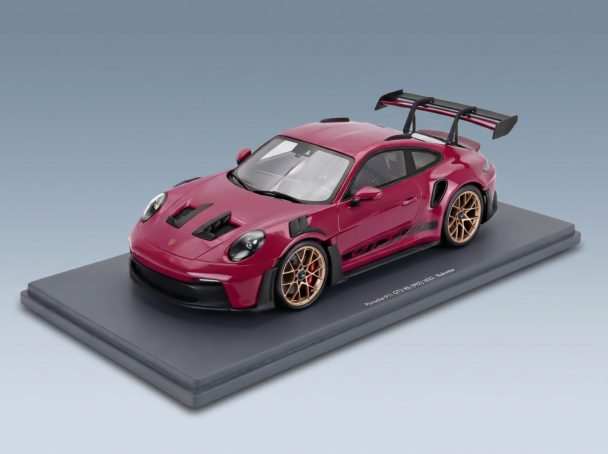 Rotes Porsche 911 GT3 RS-Modellauto im Maßstab 1:18 mit goldenen Felgen, auf Sockel präsentiert — Vroomi