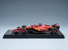 Rotes Ferrari-Modellauto mit Sponsorenlogos, präsentiert auf einem schwarzen Sockel bei Vroomi