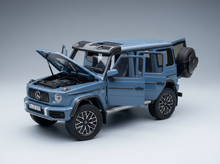Blaues Mercedes-Benz G-Wagon-Modellauto mit geöffneten Türen und Motorhaube, präsentiert von Vroomi