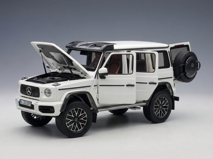 Weißes Mercedes-Benz G-Wagen-Modellauto mit geöffneten Türen und Motorhaube, präsentiert von Vroomi