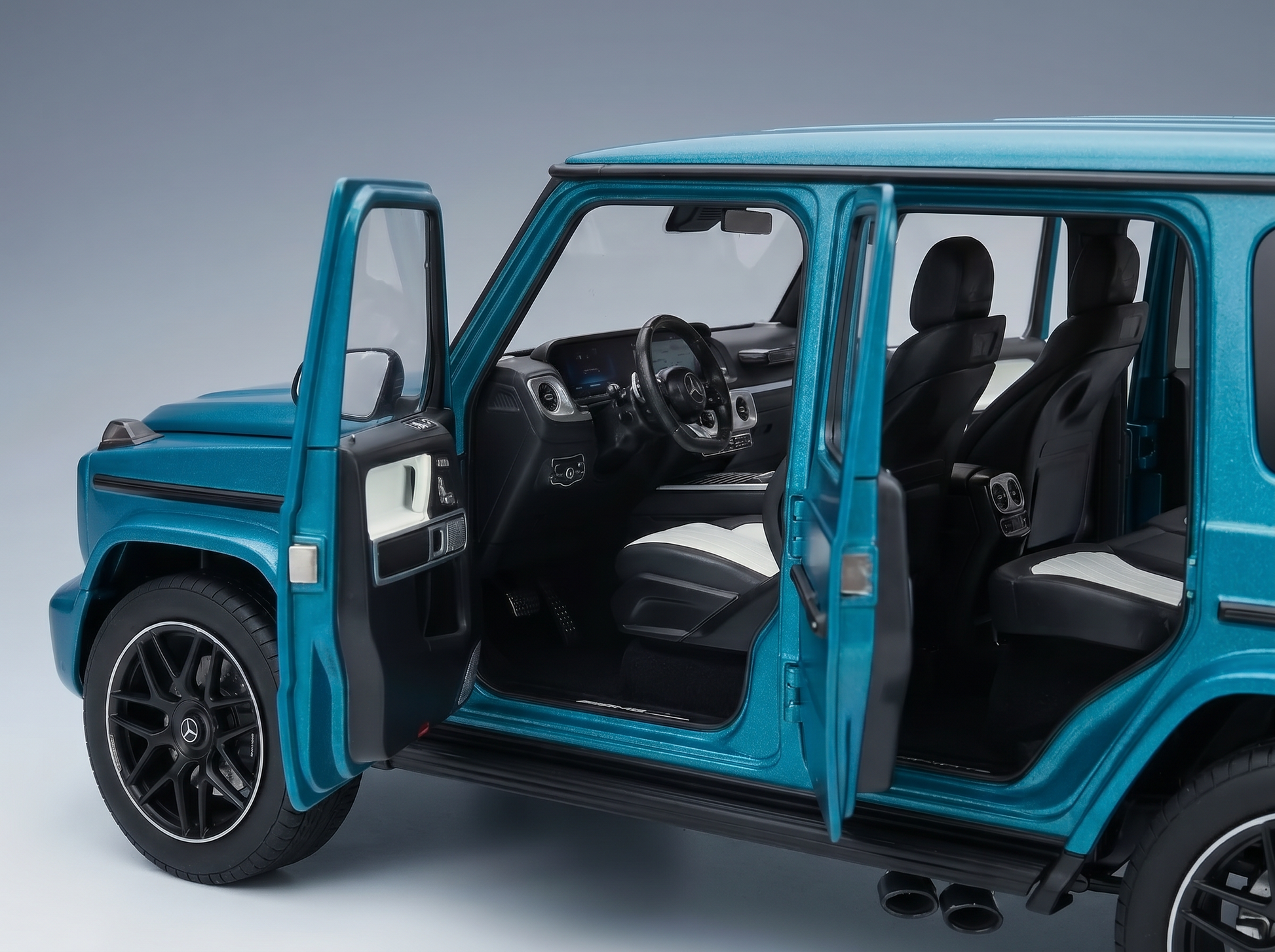 Modellauto eines Mercedes-Benz G-Wagens in der Farbe Teal mit geöffneten Türen, detailgetreuem Innenraum und Vroomi-Logo