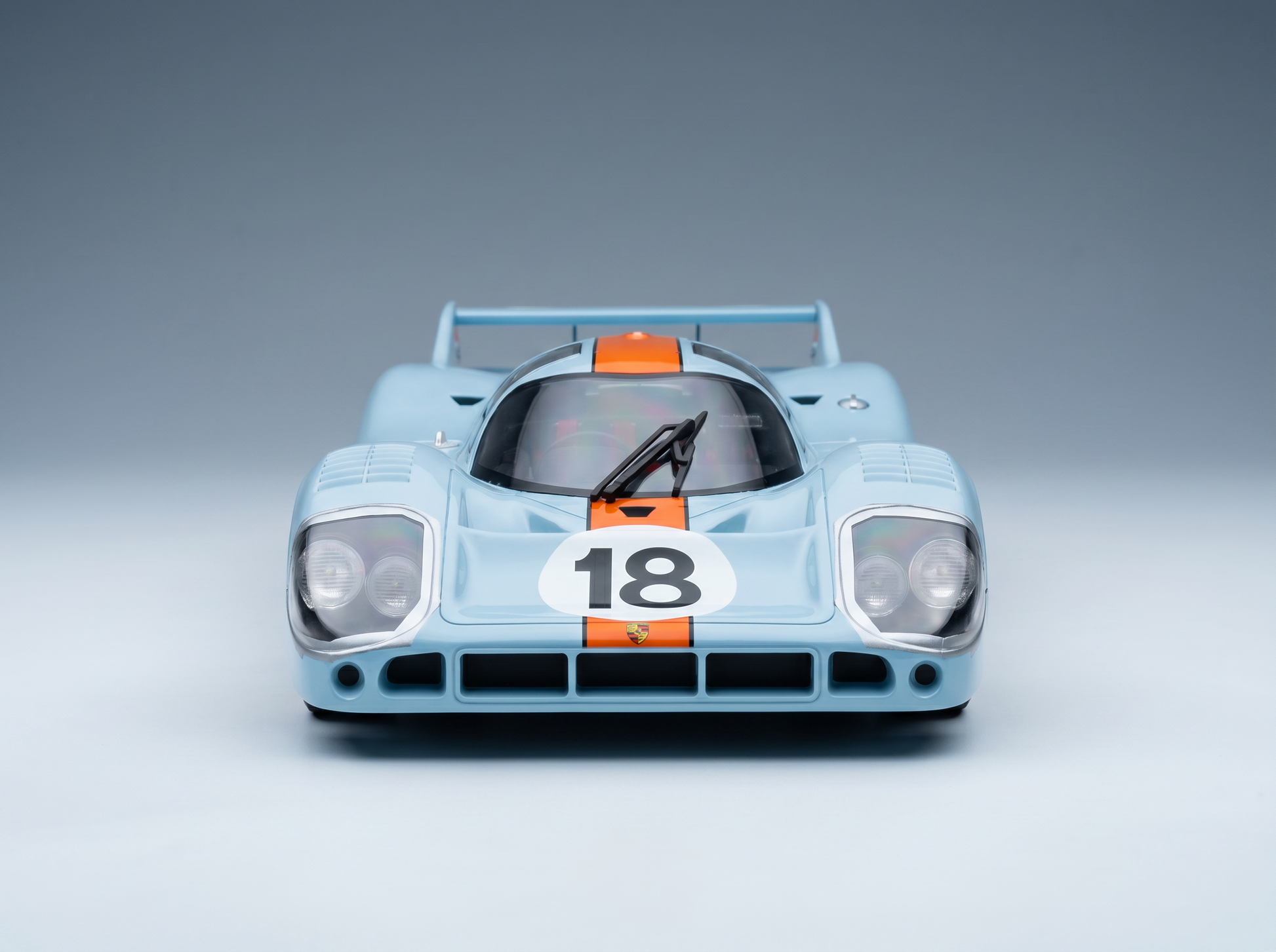 Hellblaues Porsche 917K-Modellauto mit orangefarbenen Streifen und der Nummer 18, präsentiert von Vroomi