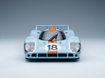 Hellblaues Porsche 917K-Modellauto mit orangefarbenen Streifen und der Nummer 18, präsentiert von Vroomi