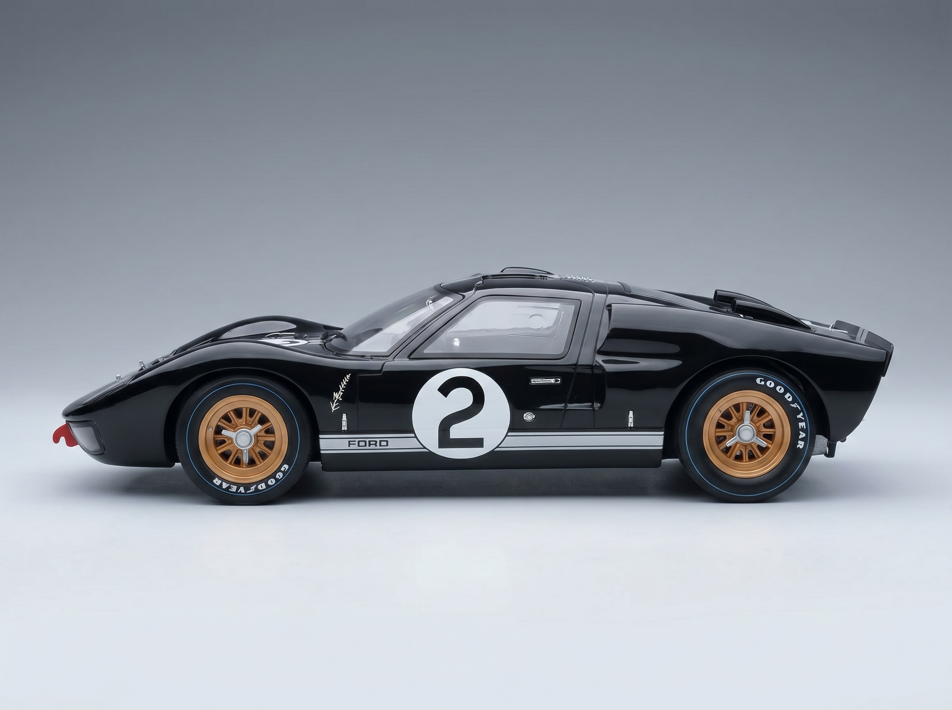 Black Ford GT40 scale model car with number 2, gold wheels, and Goodyear tires, showcased by Vroomi.