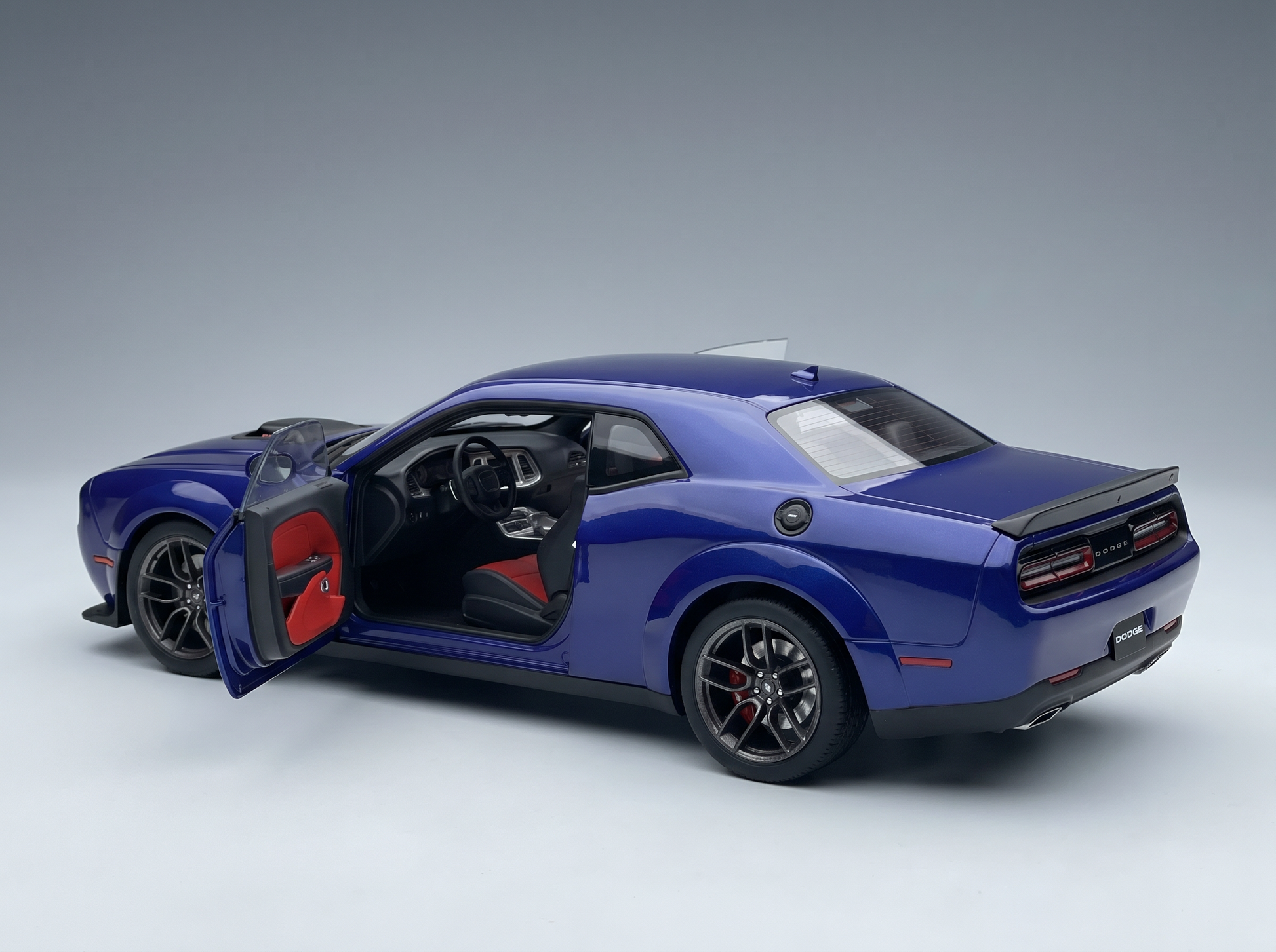 Blue Dodge Challenger scale model car with open door, red interior, at Vroomi