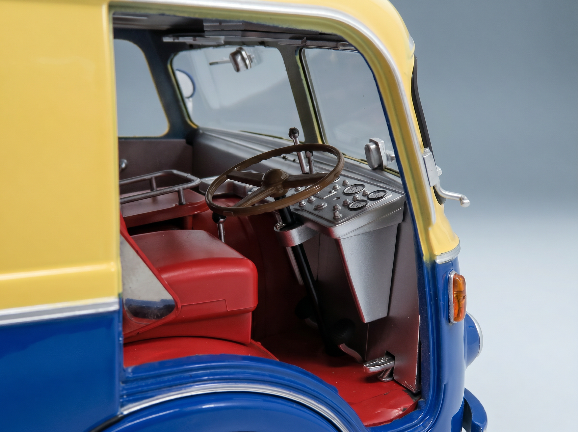 Detailed interior of a blue and yellow scale model car, featuring red seats and dashboard, from Vroomi