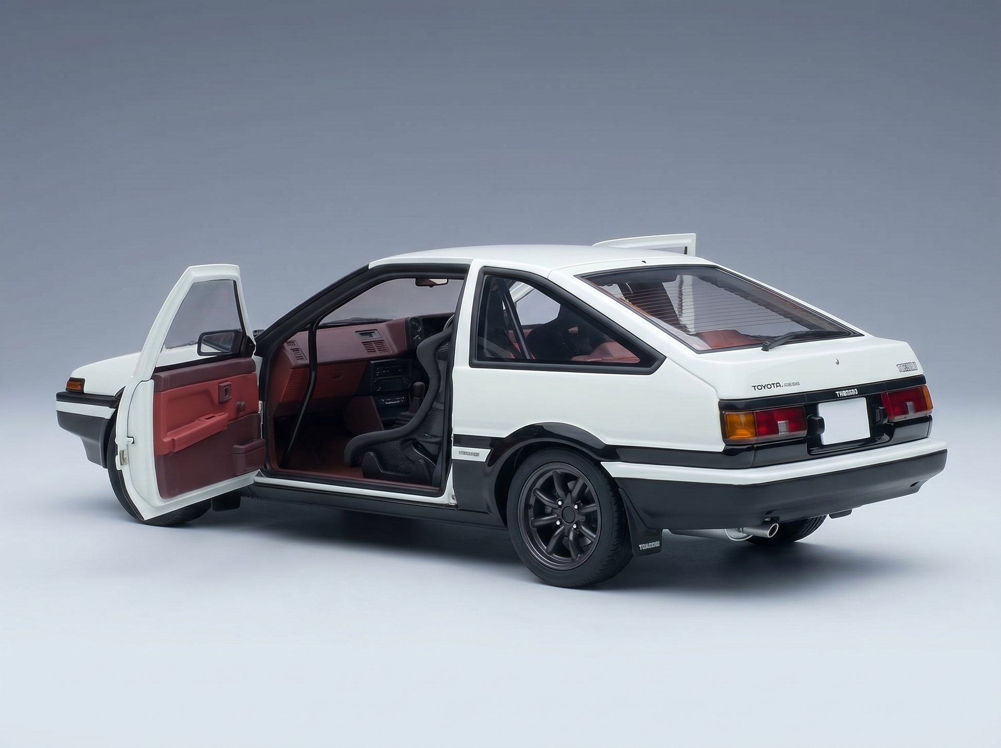 Weißes Toyota AE86-Modellauto mit geöffneten Türen und detailgetreuem Innenraum bei Vroomi