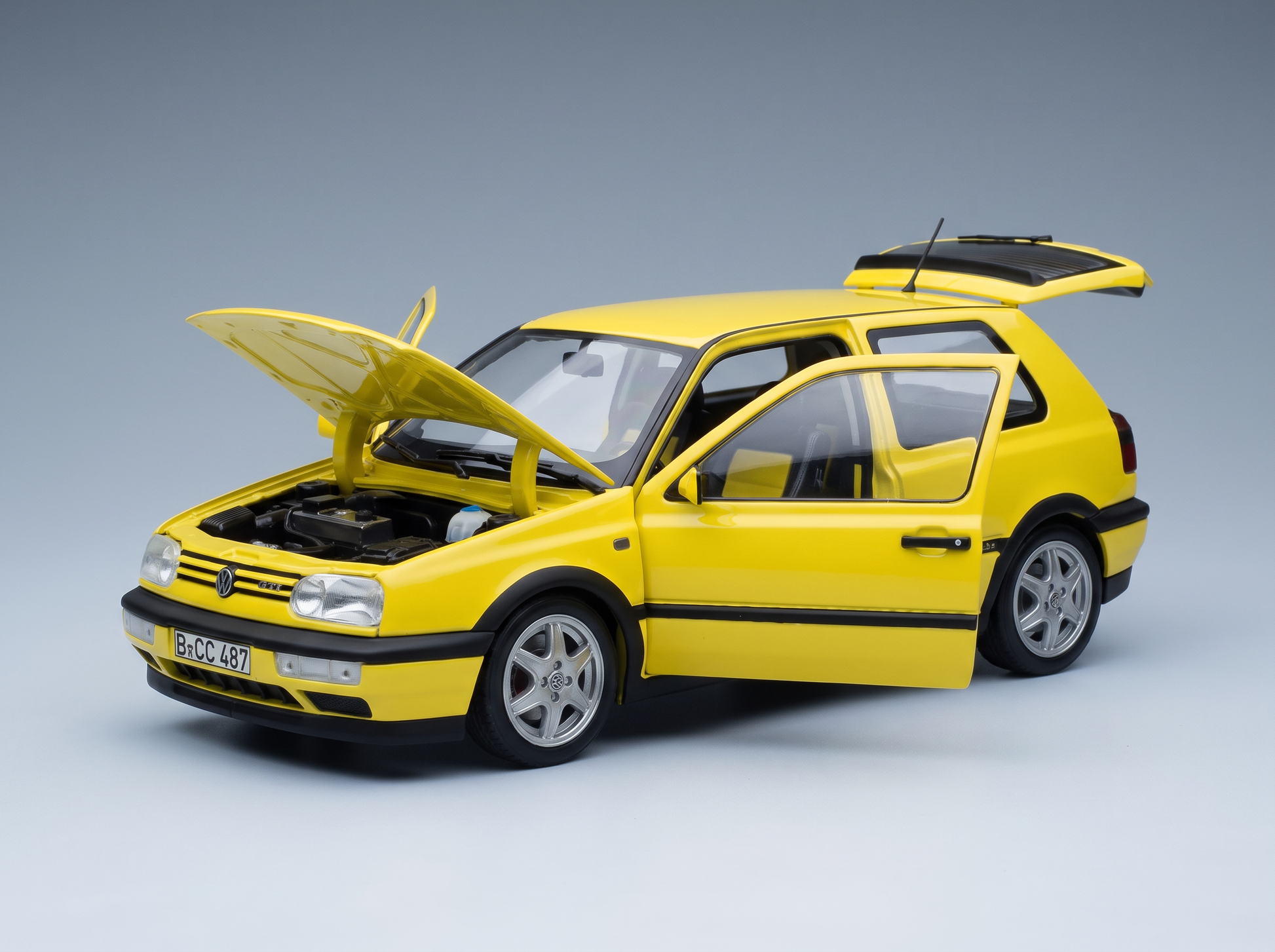 Yellow Volkswagen GTI scale model car with open hood, doors, and trunk, showcased by Vroomi for collectors.