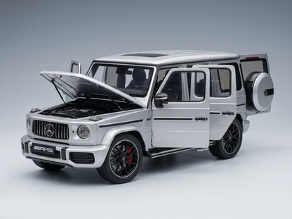 Silbernes Mercedes-AMG G63-Modellauto mit geöffneten Türen und Motorhaube sowie detailgetreuem Motor bei Vroomi